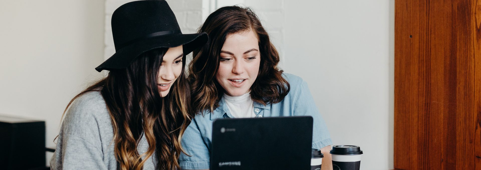 two woman sitting near table using Samsung laptop